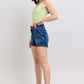 Model showcasing Judy Blue plus size double button waistband denim shorts with a green top.