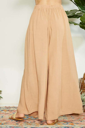 Wide leg pants with wrap pleating detail, displayed in tan color on a model, showcasing chic and flattering fit.