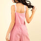 Woman in a chic pink half button drawstring sleeveless romper with a casual yet sophisticated look, perfect for a daytime outing or night out.