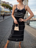 Stylish model wearing a black Bella Road Swim Openwork Spaghetti Strap Cover-Up by the beach, showcasing openwork details.