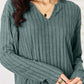 Woman wearing a ribbed notched long sleeve top from a two-piece set, in a basic style.