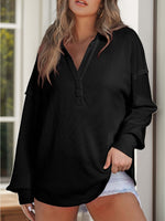 Woman wearing a black waffle-knit Johnny collar long sleeve sweatshirt with slightly stretchy fabric, paired with white shorts.