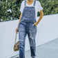 Woman wearing pocketed distressed denim overalls and white t-shirt outdoors