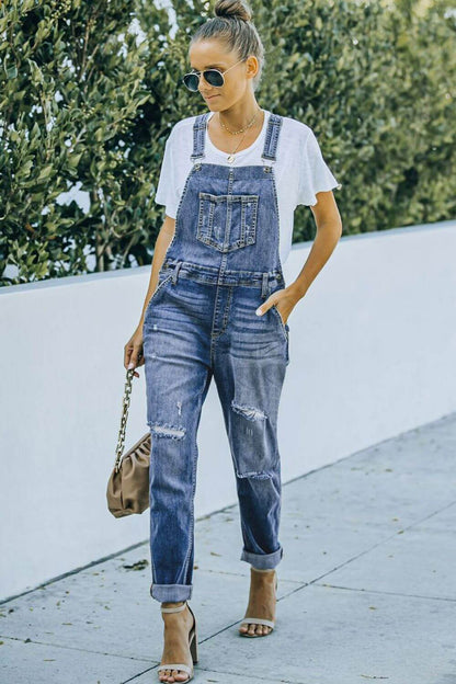 Woman wearing pocketed distressed denim overalls and white t-shirt outdoors