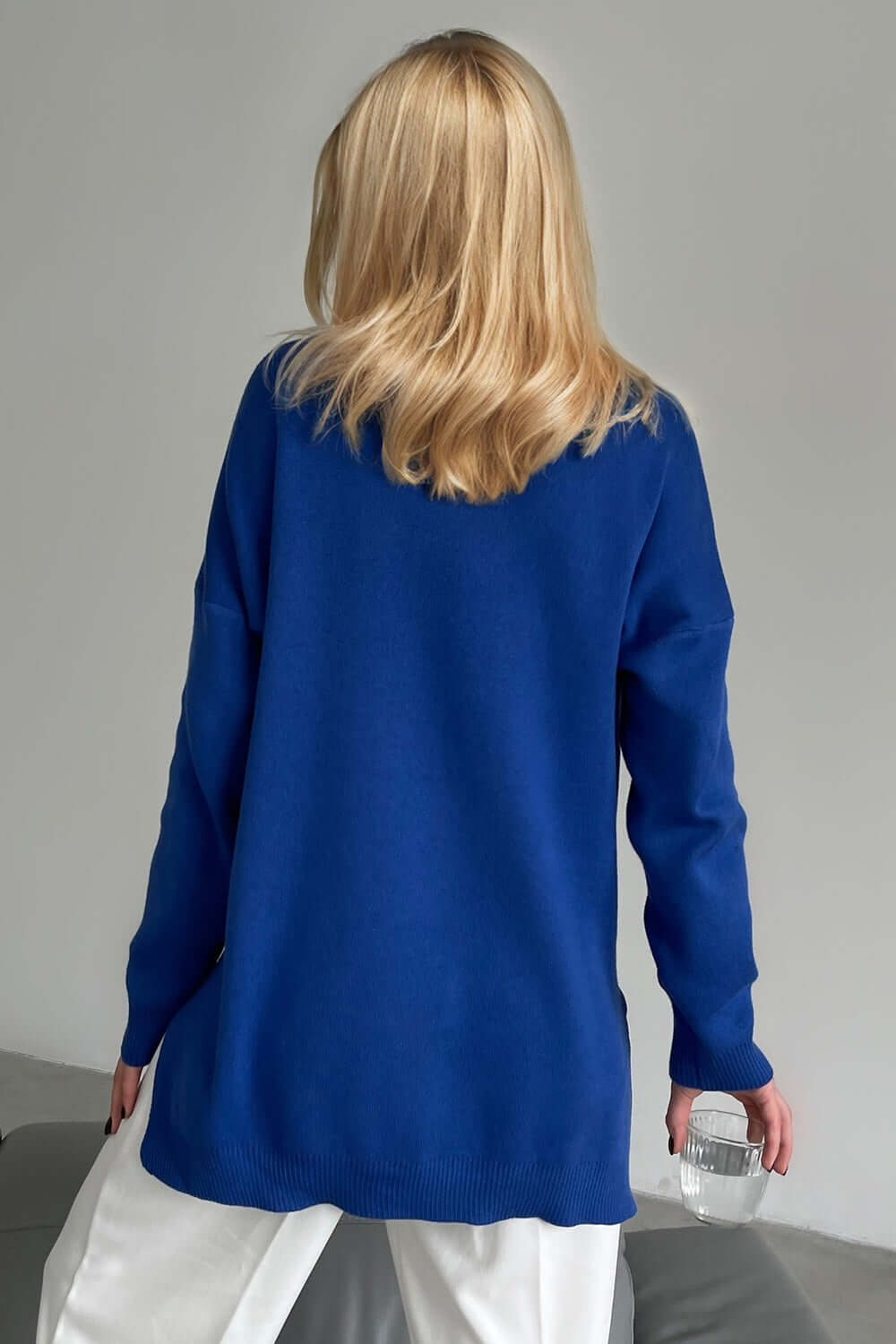 Woman wearing a blue Basic Bae Side Slit Turtleneck Sweater with dropped shoulders and white pants, chic and cozy fashion.