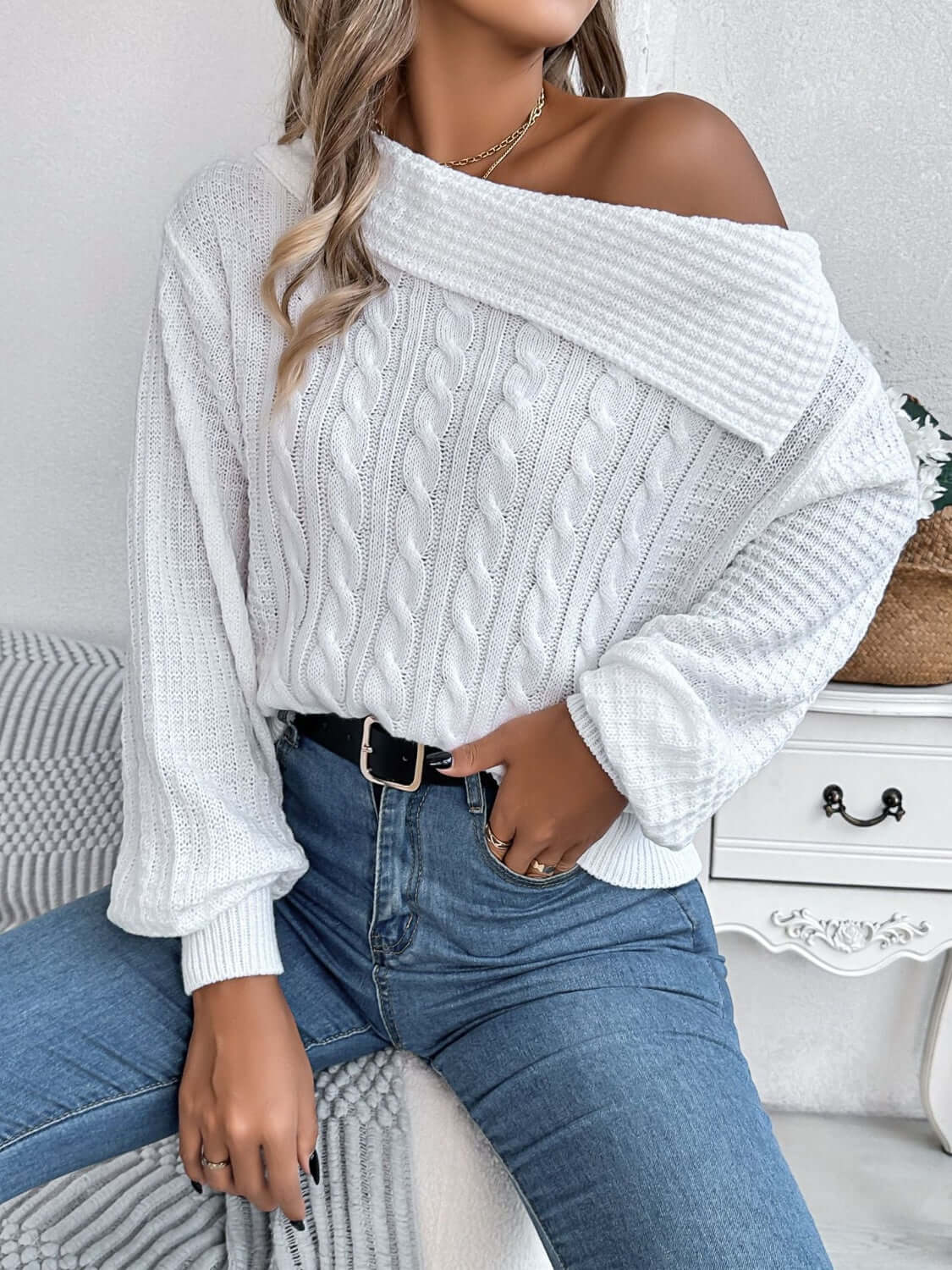 Woman wearing Bella Road Cable-Knit One Shoulder Long Sleeve Sweater in white, paired with blue jeans, showcasing the cozy and stylish design.