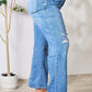 Woman wearing Judy Blue high waist distressed jeans in full size with ripped details.