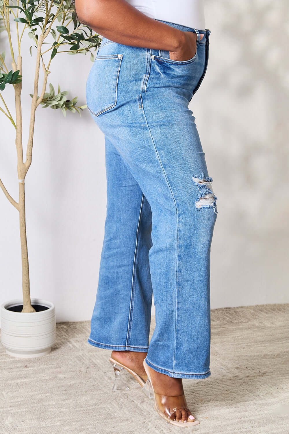 Woman wearing Judy Blue high waist distressed jeans in full size with ripped details.