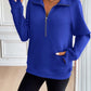 Woman wearing Ivy Lane Half Zip Raglan Sleeve Sweatshirt in blue, showcasing a stylish and comfortable look with front pocket and black shorts.