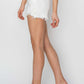 Side view of Button Fly Frayed Hem Denim Shorts in white by Risen Jeans, paired with clear heels for a chic summer look.