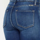 Kancan high-rise ankle skinny jeans with double waistband and release hem detail in dark wash denim, rear view.