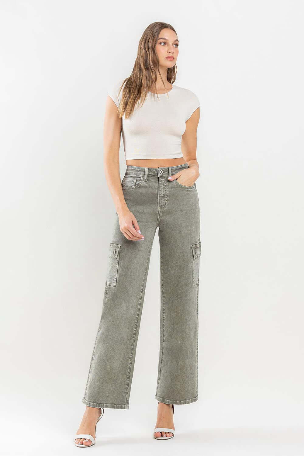 Woman wearing '90s Super High Rise Cargo Jeans with a white crop top and heels, showcasing vintage loose fit and cargo pockets.