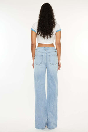 Woman wearing distressed high-waist straight jeans, back view. Comfortable and trendy denim perfect for all occasions with sneakers or heels.