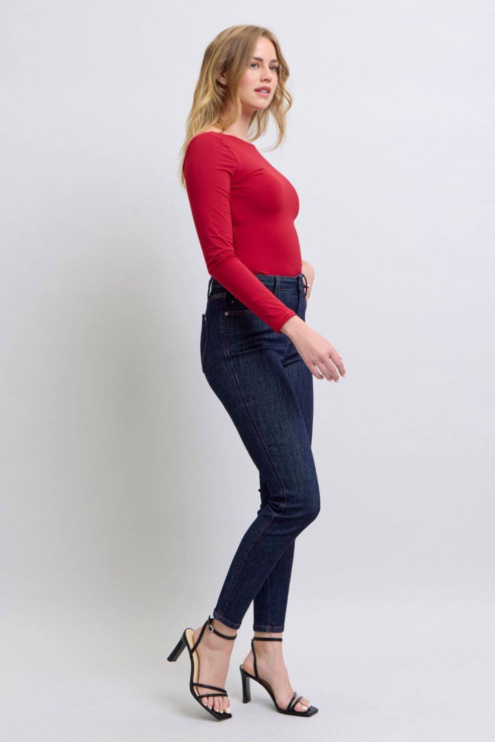 Woman wearing Judy Blue heart-shaped back pockets skinny jeans with a red top and heels.