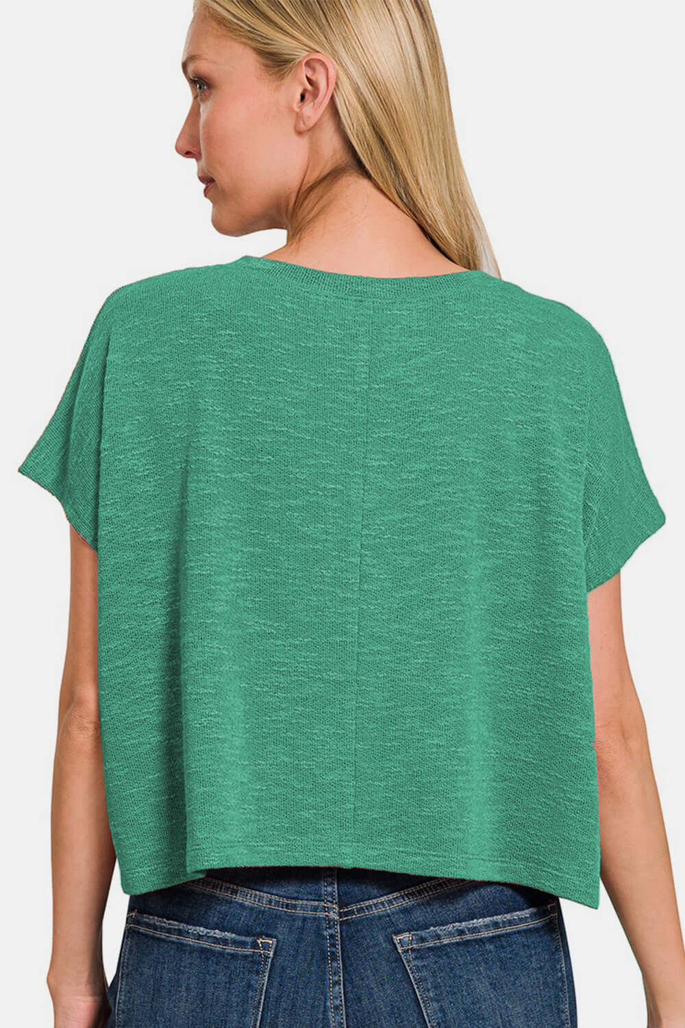 Woman wearing a green V-neck short sleeve t-shirt with jeans, view from the back.