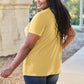 Woman wearing yellow Basic Bae Bamboo V-Neck Short Sleeve T-Shirt in outdoor setting.