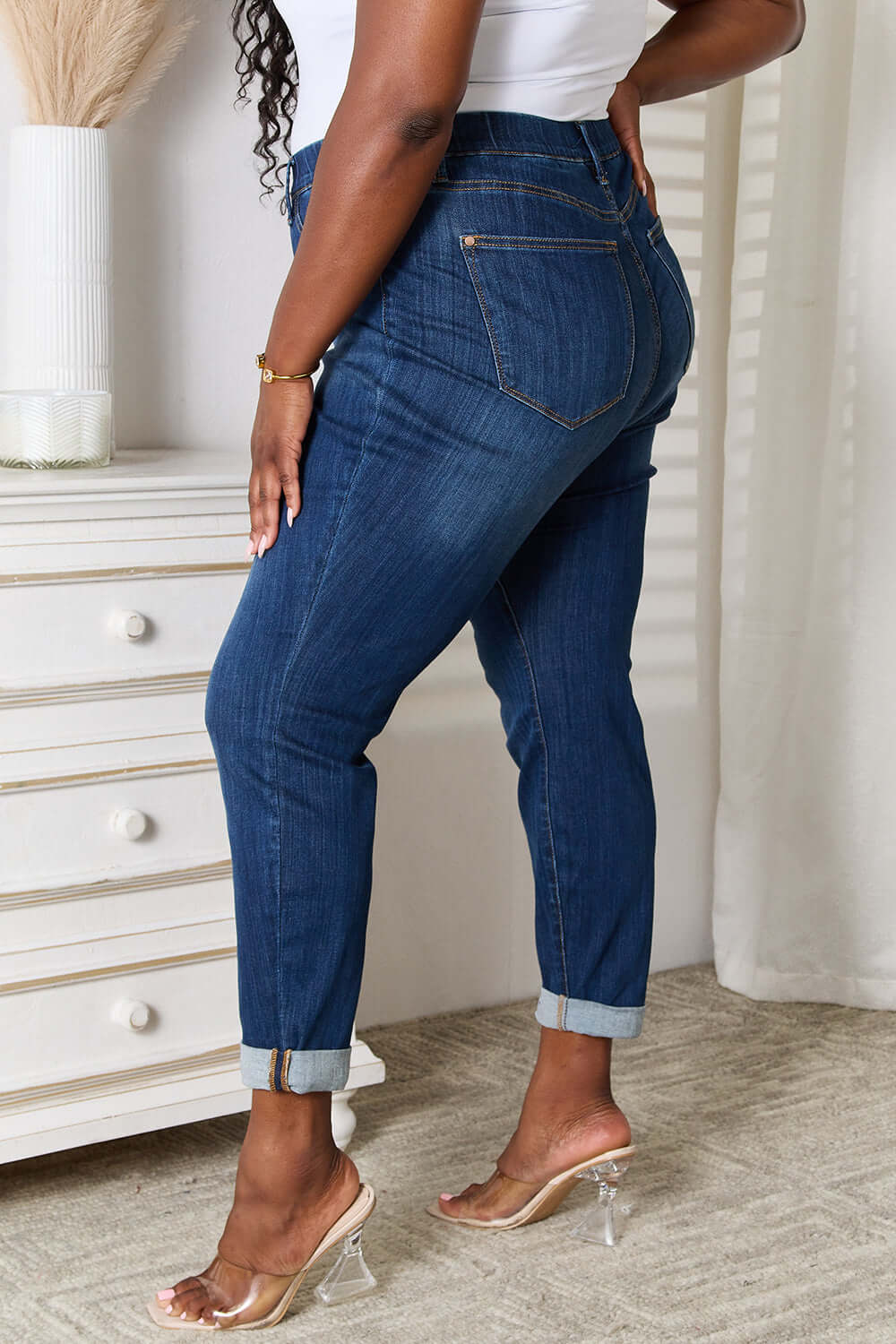 Woman wearing Skinny Cropped Judy Blue Jeans with heels, side view showing back pockets and rolled cuffs