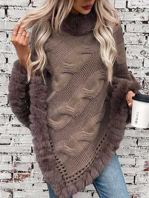 Stylish woman in a brown Bella Road Fuzzy Hem Cable-Knit Poncho, sipping coffee against a brick wall backdrop.