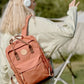 Woman wearing a large Himawari waterproof canvas backpack with side pockets and headphones in an outdoor setting.