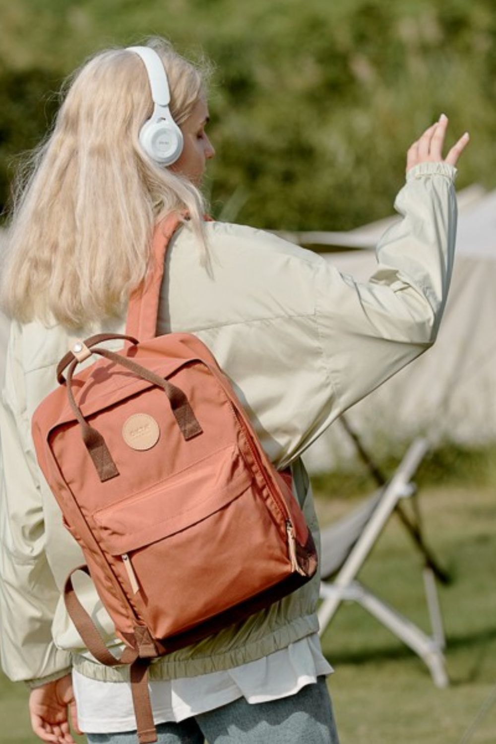 Woman wearing a large Himawari waterproof canvas backpack with side pockets and headphones in an outdoor setting.