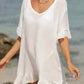 Woman wearing a sheer white tied ruffled half sleeve cover-up on the beach.