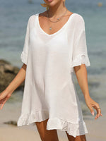 Woman wearing a sheer white tied ruffled half sleeve cover-up on the beach.