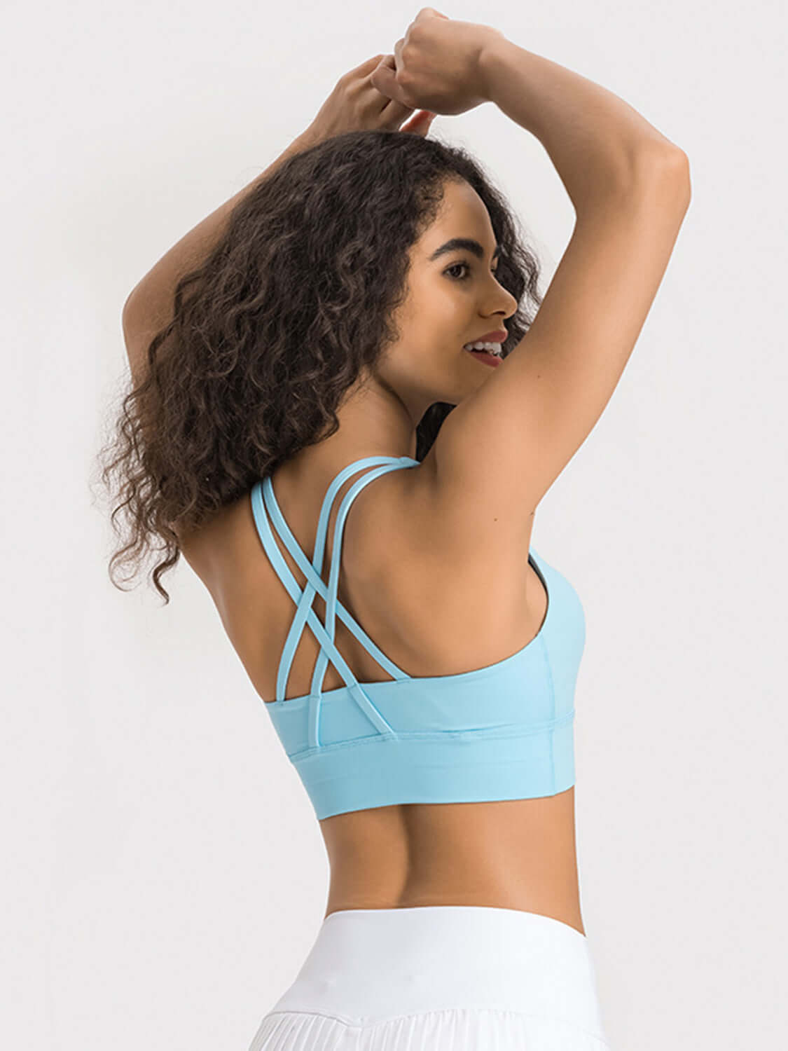 Woman showing the stylish crisscross back of a light blue active tank, perfect for workouts and comfort.