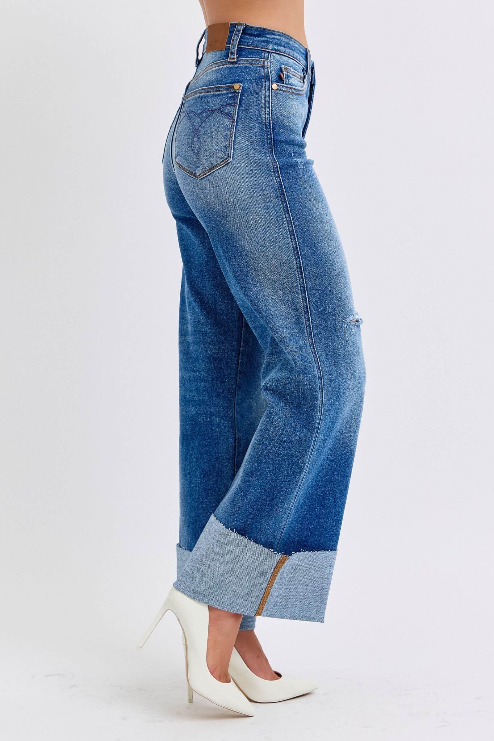 Side view of Judy Blue distressed high waist wide leg jeans showcasing a fashionable silhouette and trendy raw hem.