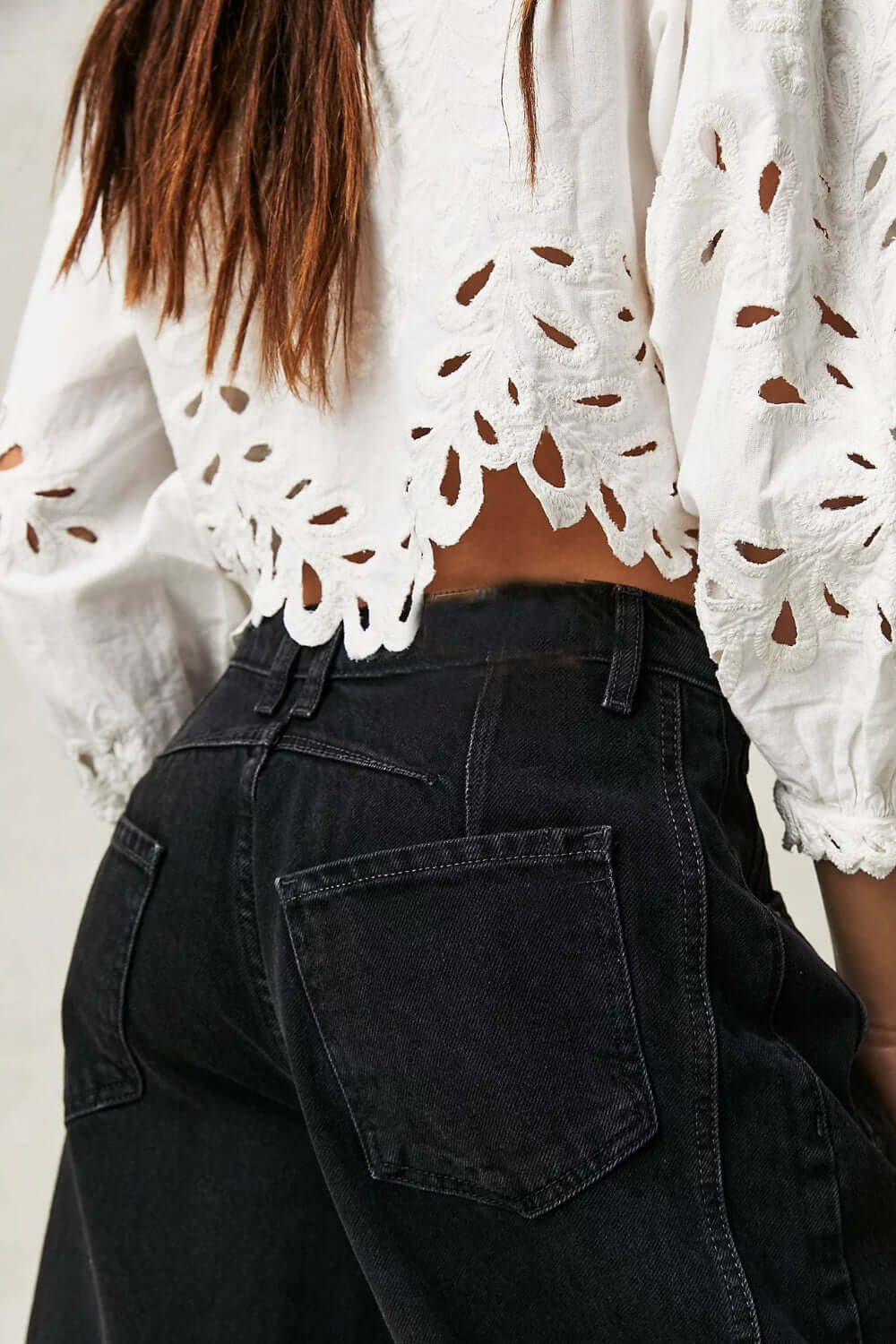 Woman wearing black wide leg jeans with back pockets and white lace crop top