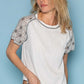 Woman wearing Lace Short Sleeve Exposed Seam T-Shirt with delicate lace detailing on sleeves and modern exposed seam design, styled with jeans.