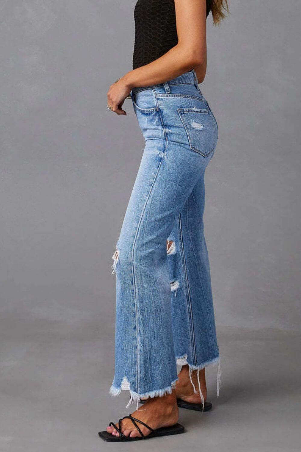 Woman wearing distressed raw hem jeans with pockets, side view.