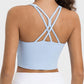 Woman wearing a light blue Millennia Crisscross Active Tank showcasing its stylish crisscross back design.