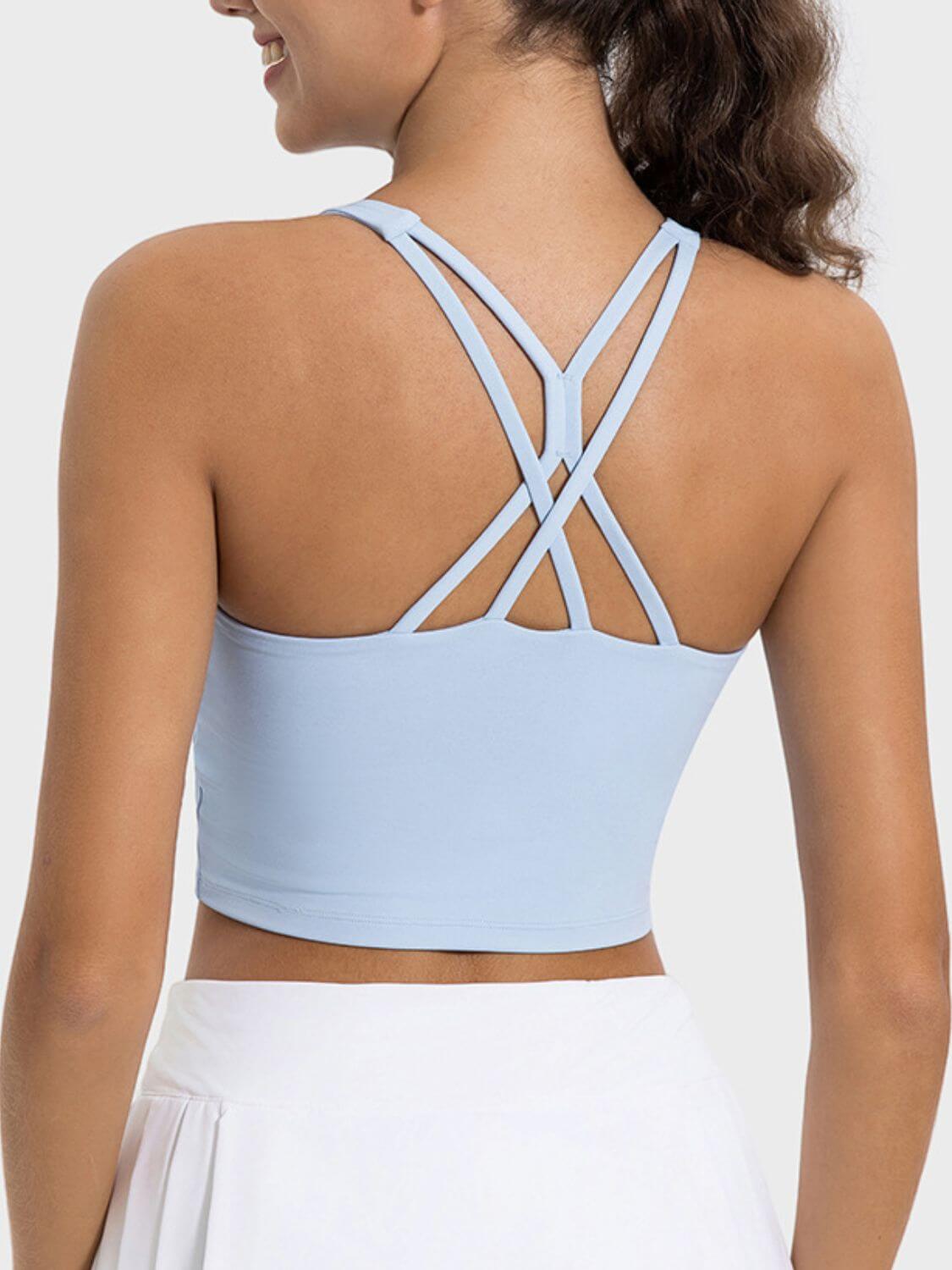 Woman wearing a light blue Millennia Crisscross Active Tank showcasing its stylish crisscross back design.