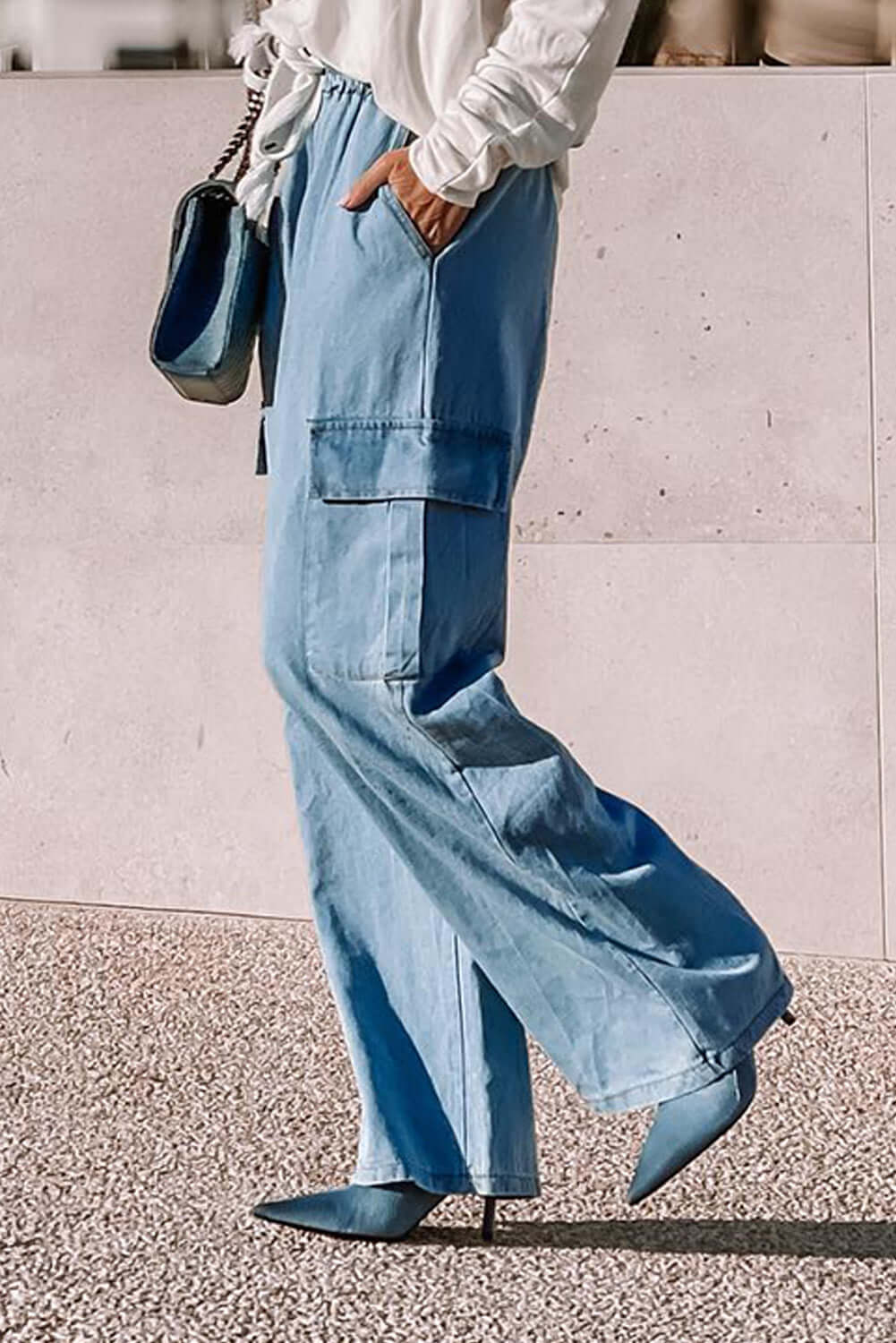 Stylish woman wearing light wash Bella Road Denim wide leg jeans with cargo pockets and a drawstring, paired with heels.