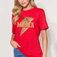 Woman wearing red MAMA round neck short sleeve T-shirt with lightning bolt graphic, paired with blue jeans.