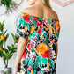 Woman wearing a colorful floral off-shoulder top with a summery and feminine vibe, perfect for warm weather outings.