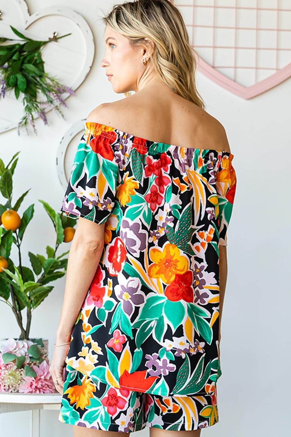 Woman wearing a colorful floral off-shoulder top with a summery and feminine vibe, perfect for warm weather outings.