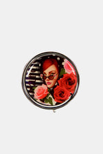 Nicole Lee USA Print Metallic Circular Large Pill Case with floral and female design on a silver-tone metal exterior.