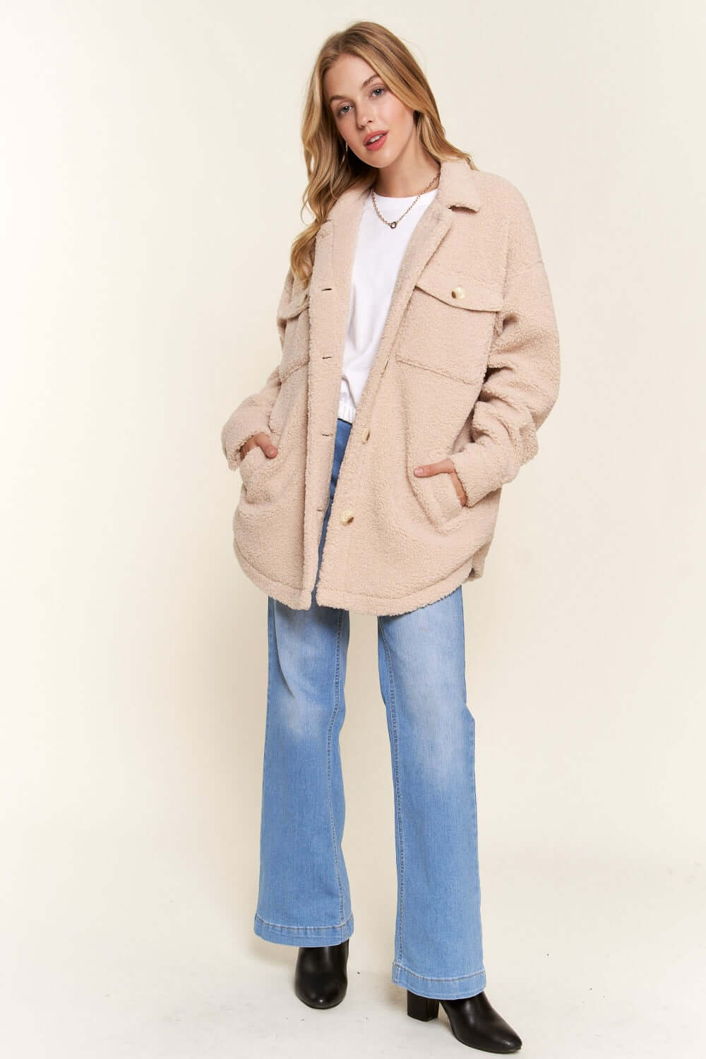 Cozy teddy sherpa button-down shacket with curved hem, styled with jeans and boots for a chic casual look.