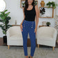 Woman wearing FAM-FAM High Waist Skinny Pants in blue with decorative buttons, styled elegantly with a black top in a chic room.