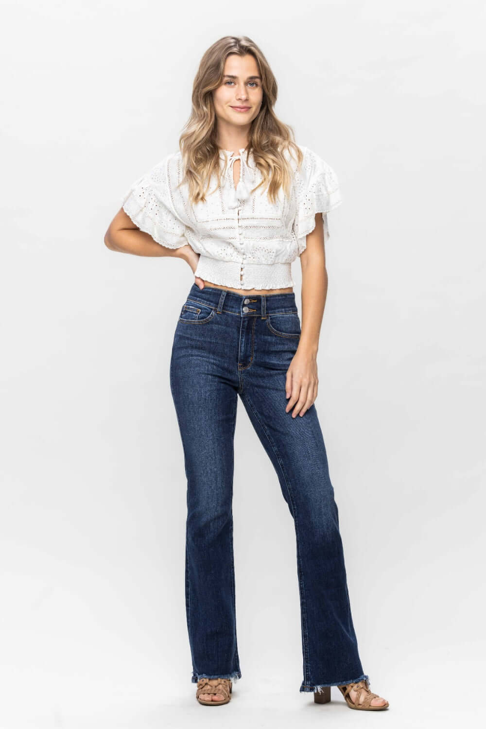 Woman wearing Judy Blue Frayed Hem Bootcut Jeans with white lace top and sandals