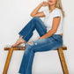 Model showcases bytos Full Size Raw Hem Distressed Mid Rise Straight Jeans, pairing them with a classic white tee and stylish heels.