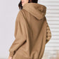 Woman wearing RISEN drawstring drop shoulder long sleeve hoodie in beige, showing back view, with comfortable fit and trendy design.