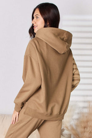 Woman wearing RISEN drawstring drop shoulder long sleeve hoodie in beige, showing back view, with comfortable fit and trendy design.