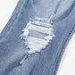 Close-up of distressed raw hem on slightly stretchy bootcut jeans made from cotton, polyester, and elastane blend.