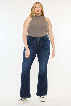 Woman wearing Mid Rise Flare Jeans in dark stone wash with a sleeveless top, showcasing a flattering fit for petite frames.