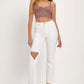 Woman wearing white distressed cropped straight jeans and a mauve crop top, showcasing an edgy and fashionable look.