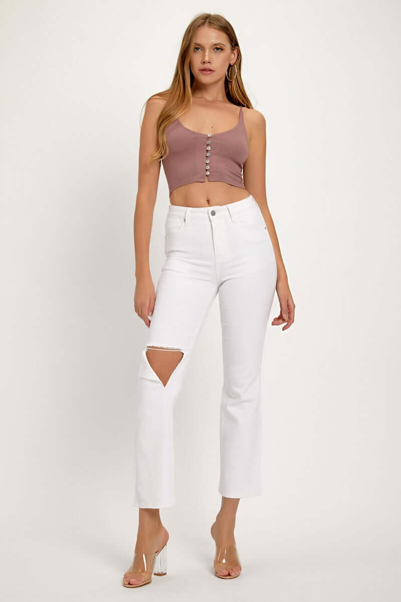 Woman wearing white distressed cropped straight jeans and a mauve crop top, showcasing an edgy and fashionable look.