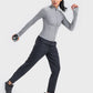 Woman in a gray zip-up long sleeve sports jacket, stylishly exercising with a dumbbell in hand. Perfect for any active lifestyle!