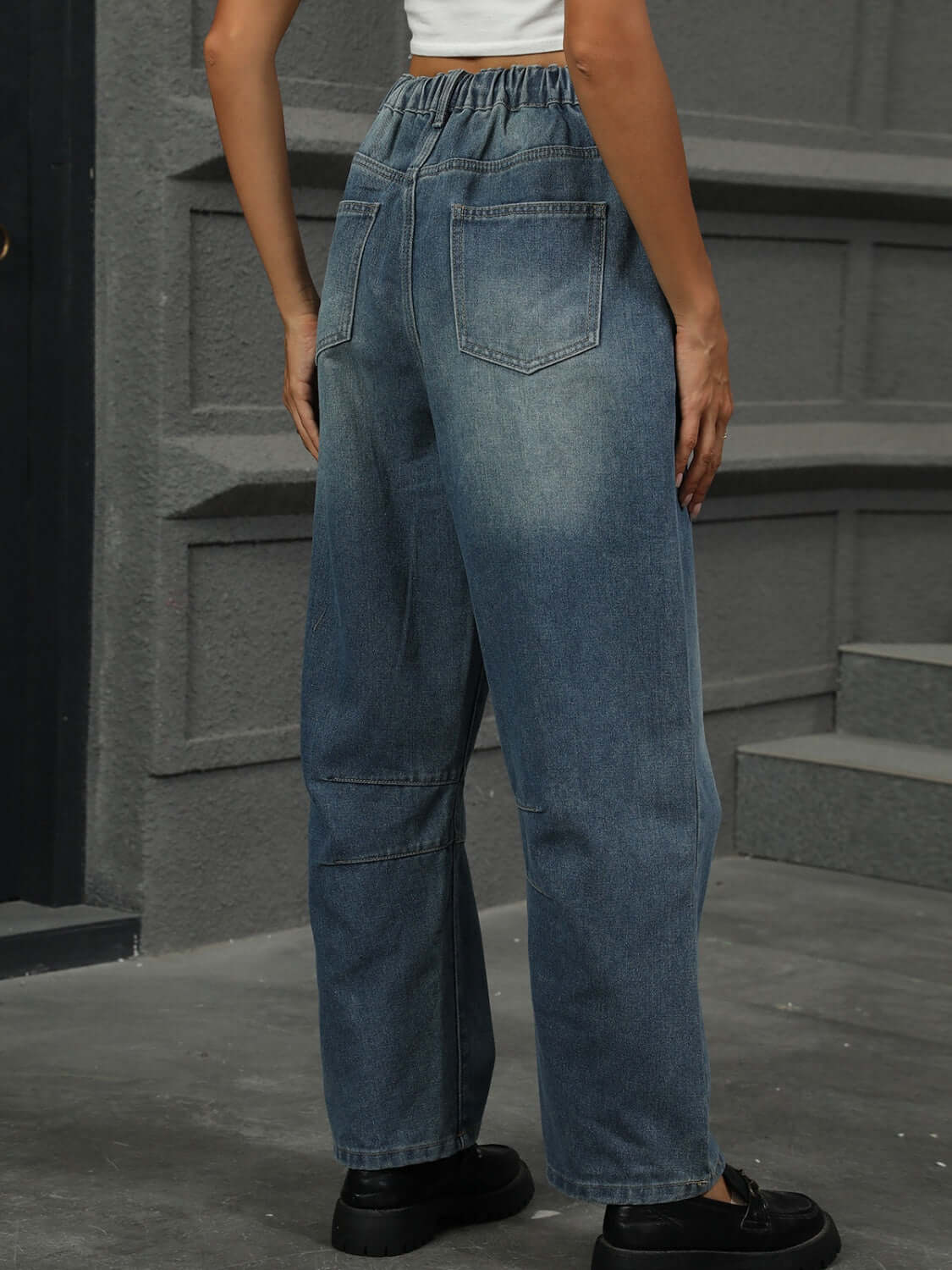 Woman wearing half elastic waist straight leg jeans in medium wash, showcasing back view and pocket details.